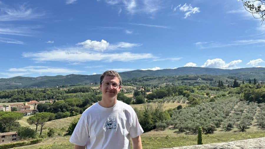 Aidan standing on a hillside overlooking the Tuscan countryside